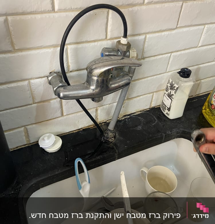 ברז מטבח עם צינור שחור וכלים בכיור
